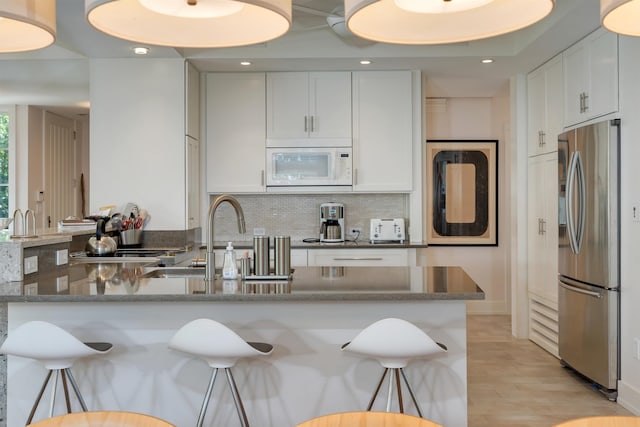 312 S Lake Dr, Cape May Point, NJ 08212 - kitchen with stainless steel fridge with ice dispenser, white microwave, a peninsula, white cabinetry, and a kitchen breakfast bar