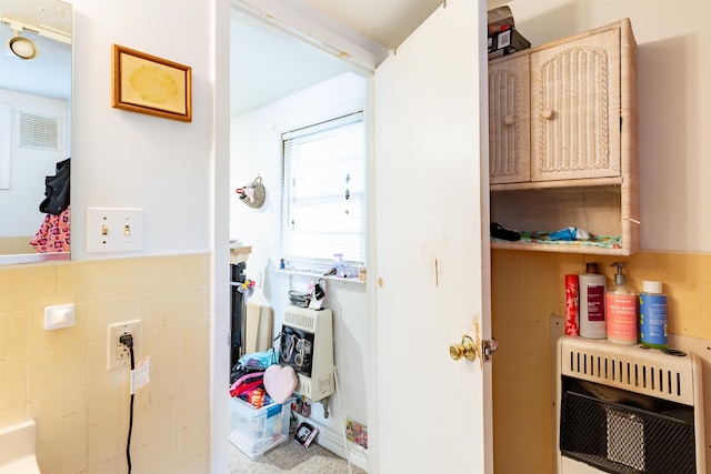 laundry room featuring heating unit and tile walls