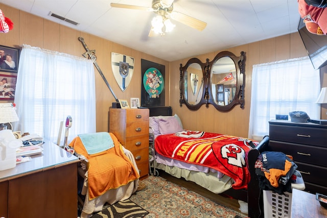 bedroom featuring wood walls and ceiling fan