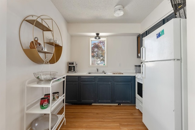 kitchen with a textured ceiling, white refrigerator, light hardwood / wood-style flooring, and sink