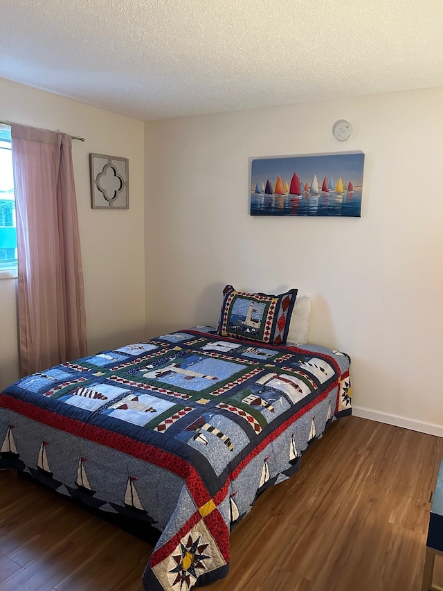 bedroom featuring dark hardwood / wood-style flooring and a textured ceiling