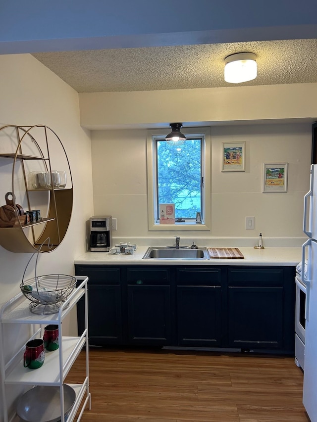 kitchen with a textured ceiling, sink, and hardwood / wood-style flooring