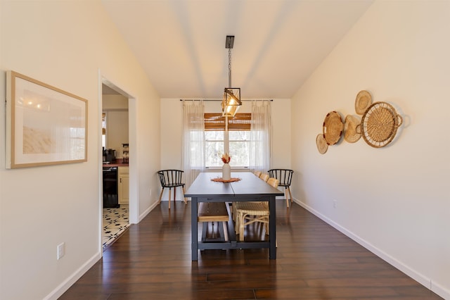 dining area featuring dark wood-type flooring, baseboards, and vaulted ceiling