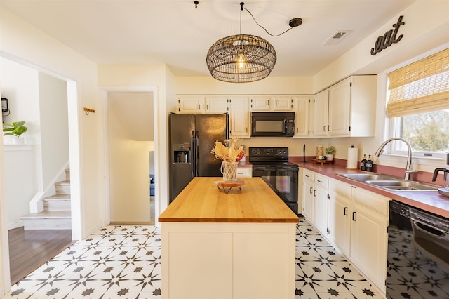 kitchen featuring light floors, butcher block counters, black appliances, and a sink