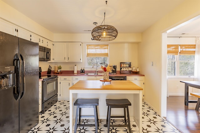 kitchen featuring a sink, black appliances, white cabinets, and wood counters