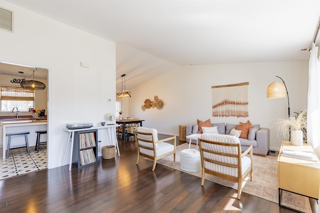 living area featuring visible vents, wood finished floors, and vaulted ceiling