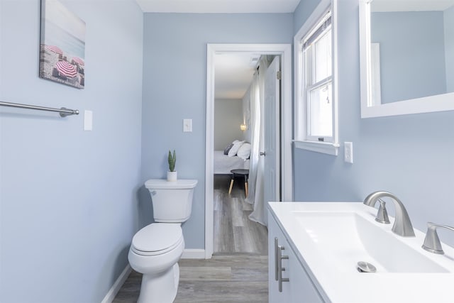 bathroom featuring baseboards, toilet, wood finished floors, and vanity