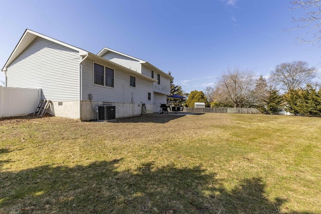 rear view of property with cooling unit, a lawn, and fence