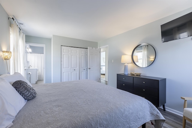 bedroom with visible vents, wood finished floors, connected bathroom, a closet, and baseboards