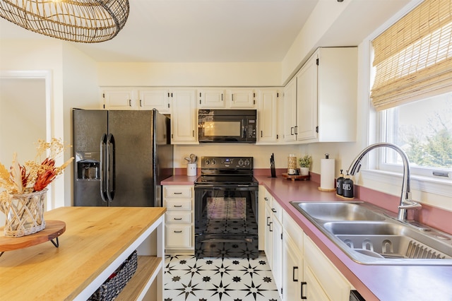 kitchen featuring a sink, light floors, black appliances, and white cabinets