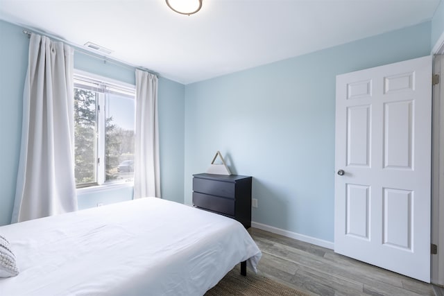 bedroom featuring wood finished floors, visible vents, and baseboards