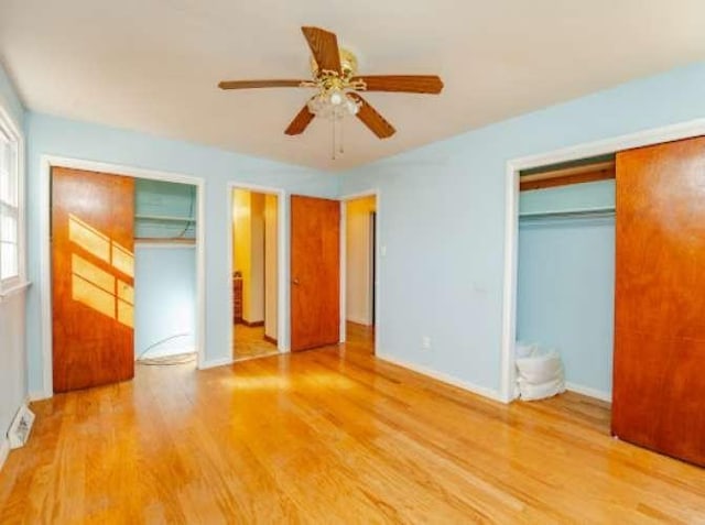 unfurnished bedroom featuring hardwood / wood-style flooring, multiple closets, and ceiling fan