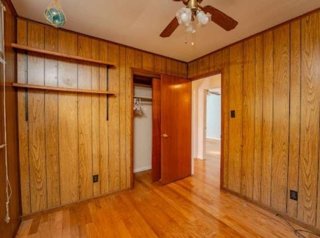 unfurnished bedroom with wooden walls and light hardwood / wood-style flooring