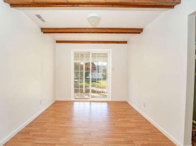 spare room with beamed ceiling and light hardwood / wood-style floors