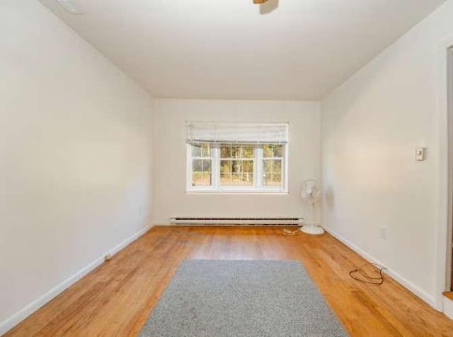 empty room featuring a baseboard radiator and wood-type flooring