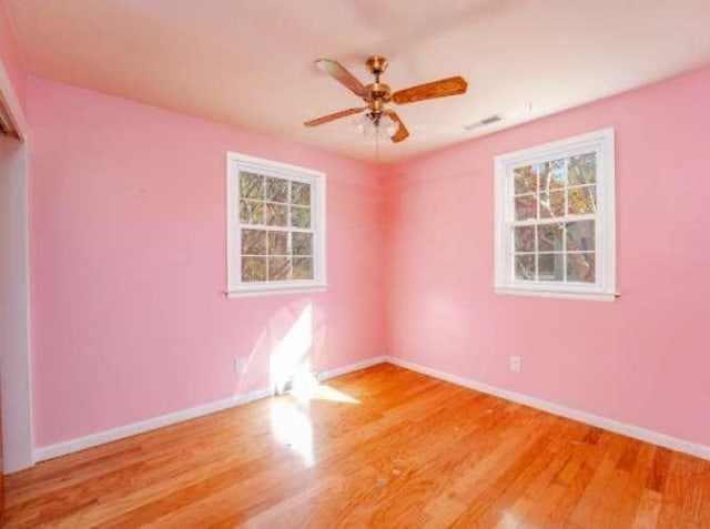 unfurnished room featuring a wealth of natural light, ceiling fan, and light wood-type flooring