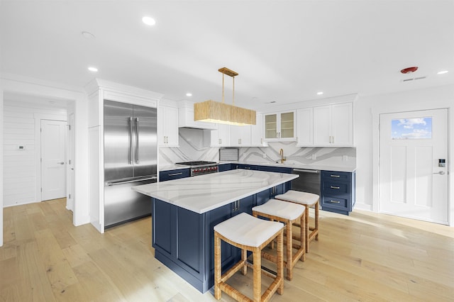 kitchen with white cabinetry, a center island, hanging light fixtures, a breakfast bar, and appliances with stainless steel finishes