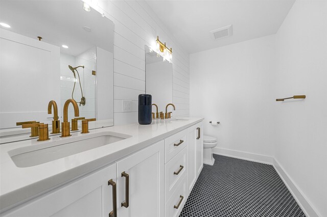 bathroom featuring a tile shower, vanity, and toilet