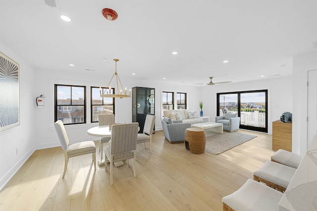 living room featuring ceiling fan with notable chandelier and light hardwood / wood-style flooring