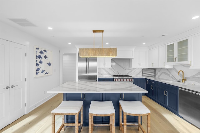 kitchen featuring blue cabinetry, a kitchen island, pendant lighting, white cabinets, and appliances with stainless steel finishes