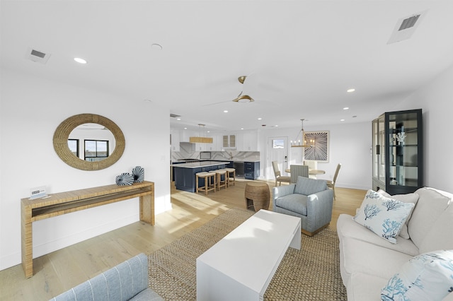 living room with light hardwood / wood-style flooring and ceiling fan with notable chandelier