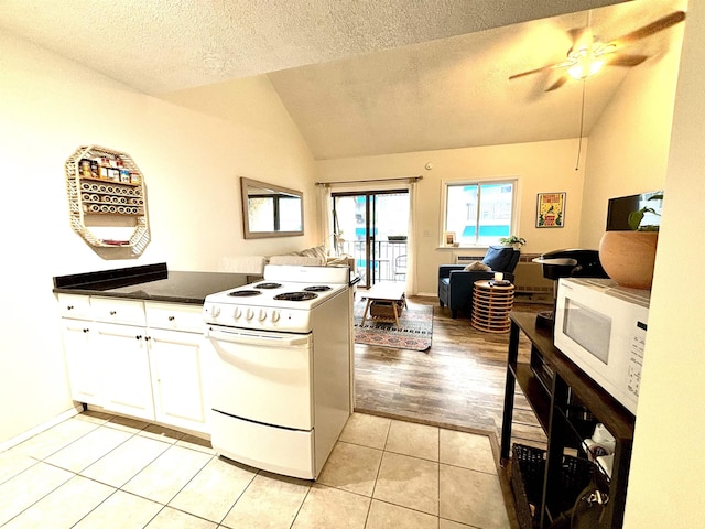 kitchen featuring white appliances, a textured ceiling, light tile patterned floors, white cabinetry, and lofted ceiling