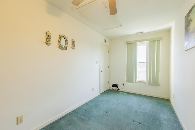 carpeted spare room with visible vents, attic access, and baseboards