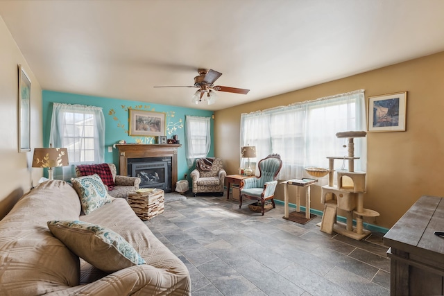 living room featuring plenty of natural light, a fireplace, baseboards, and ceiling fan