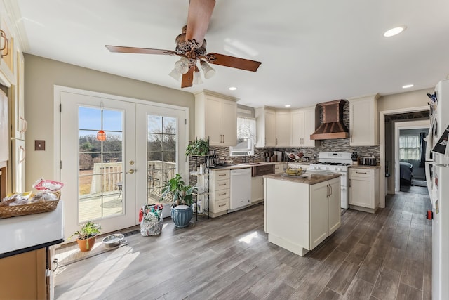 kitchen featuring backsplash, white appliances, french doors, and wall chimney range hood