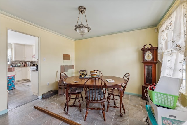 dining space with crown molding, baseboards, and stone tile flooring