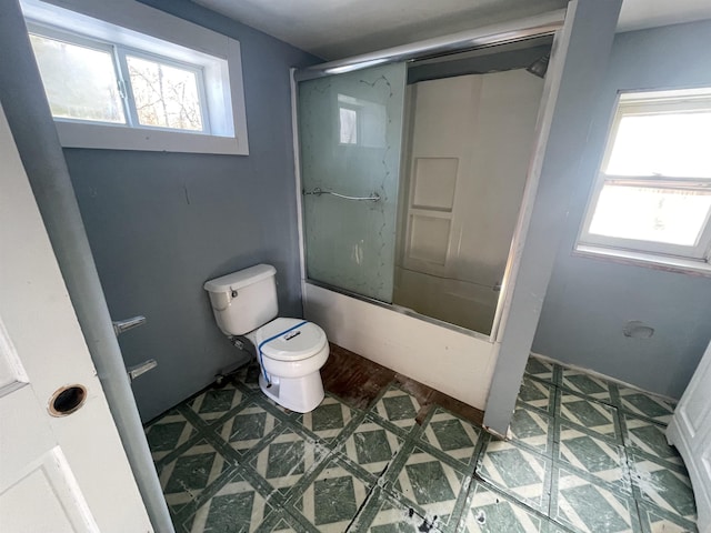 bathroom with toilet and combined bath / shower with glass door