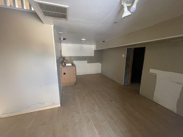 basement with sink and light hardwood / wood-style flooring