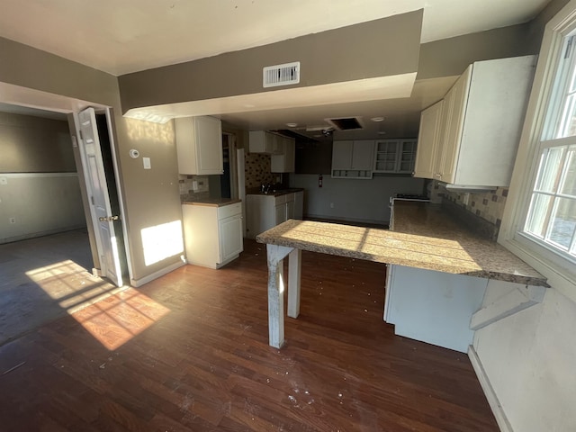 kitchen with dark hardwood / wood-style flooring, white cabinets, backsplash, and kitchen peninsula