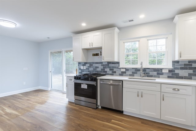 kitchen featuring white cabinetry, sink, stainless steel appliances, light hardwood / wood-style floors, and decorative backsplash