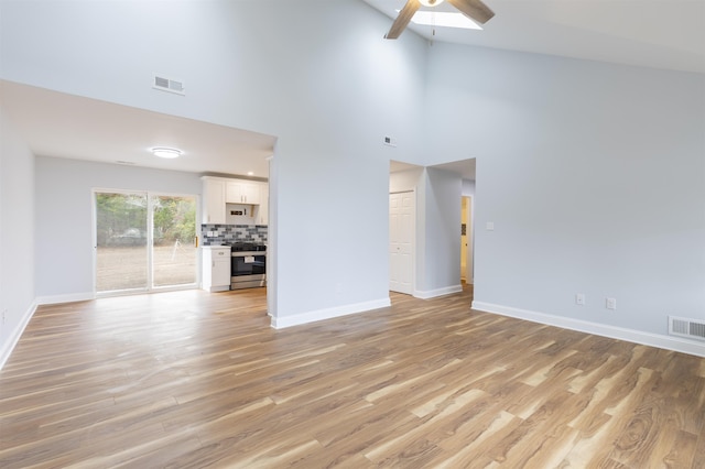 unfurnished living room with ceiling fan, high vaulted ceiling, and light wood-type flooring