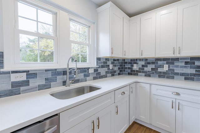 kitchen featuring white cabinets, backsplash, stainless steel dishwasher, and sink