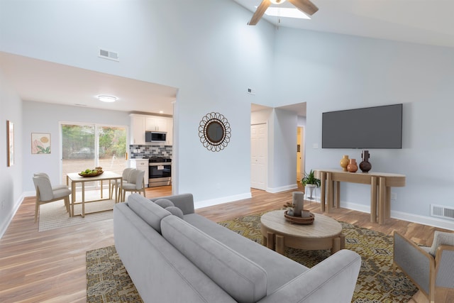 living room featuring light hardwood / wood-style floors, high vaulted ceiling, and ceiling fan