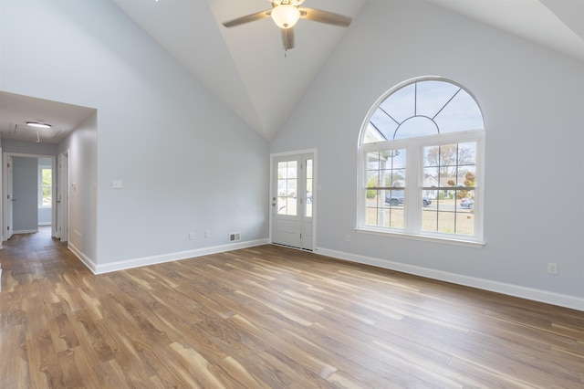 empty room featuring ceiling fan, light wood-type flooring, and high vaulted ceiling