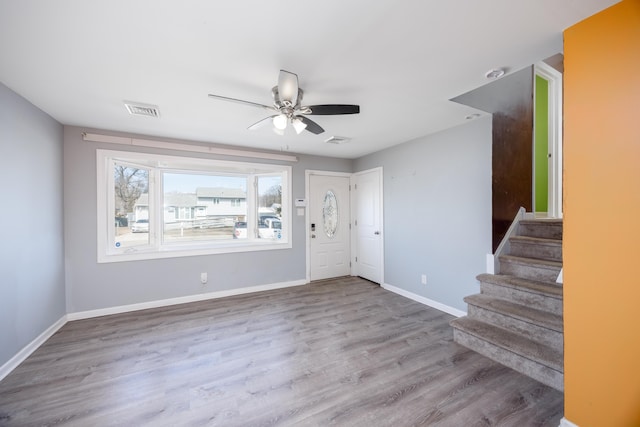 foyer with visible vents, stairway, ceiling fan, wood finished floors, and baseboards