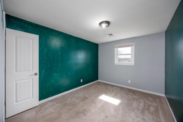 spare room with carpet flooring, visible vents, and baseboards