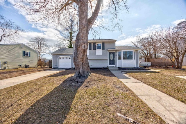 tri-level home featuring a garage, concrete driveway, fence, and central air condition unit