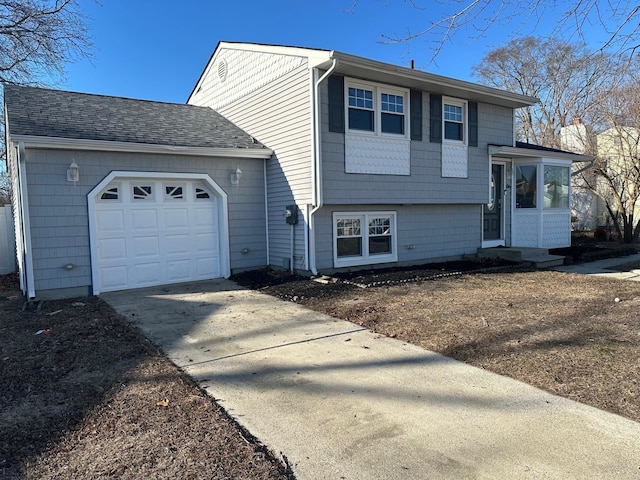 split level home featuring a shingled roof, concrete driveway, and an attached garage