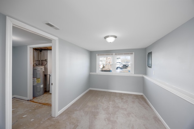 empty room featuring baseboards, visible vents, and electric water heater