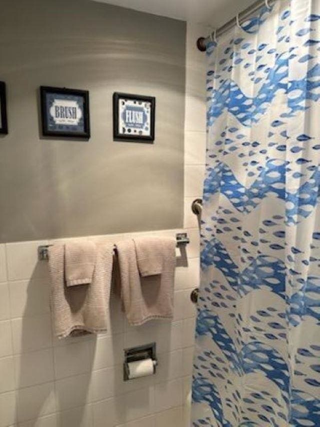 bathroom featuring a shower with curtain and tile walls