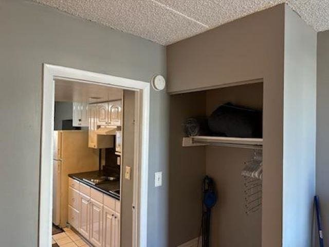 kitchen with stainless steel fridge, light tile patterned flooring, and a textured ceiling