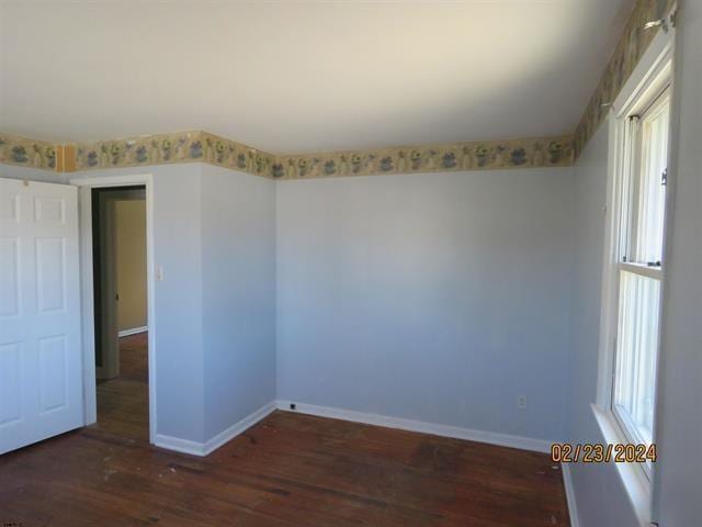 empty room with plenty of natural light, baseboards, and wood finished floors