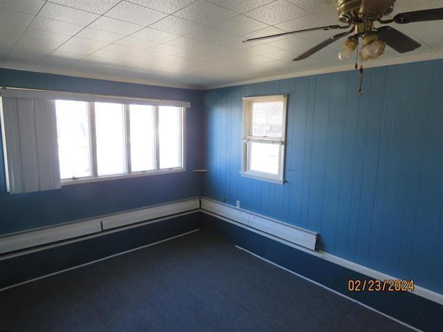 spare room featuring baseboard heating, a ceiling fan, and crown molding