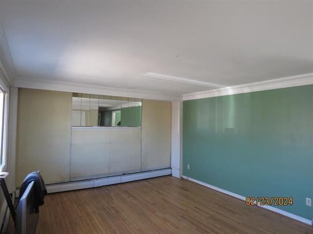 unfurnished room with a baseboard radiator, crown molding, baseboards, and wood finished floors