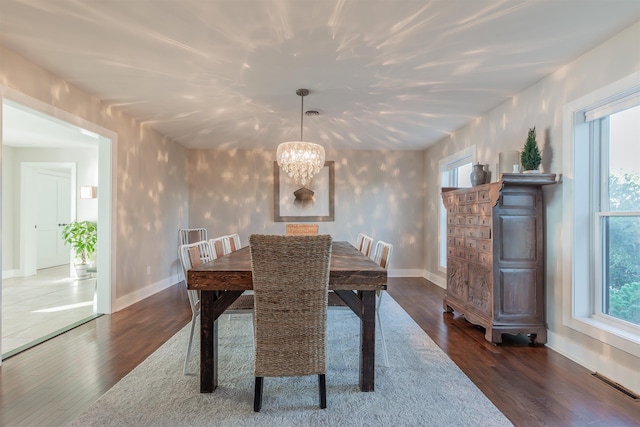 dining area featuring a wealth of natural light, dark wood-type flooring, and a notable chandelier