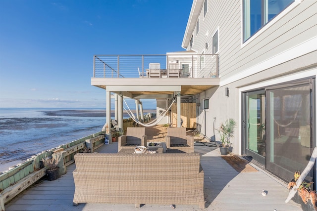 deck with an outdoor living space, a water view, and a beach view